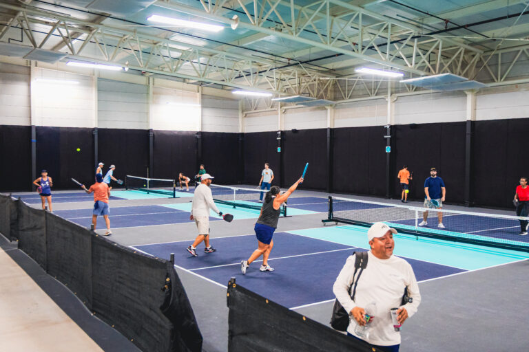 Players competing across multiple indoor pickleball courts during an event at Texas Pickle Hall